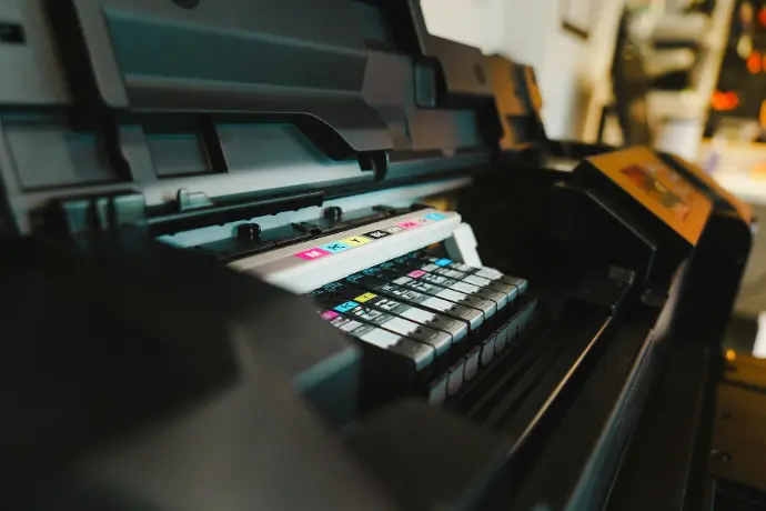 Una vista de cerca de un plotter abierto donde se ven los cartuchos de tinta